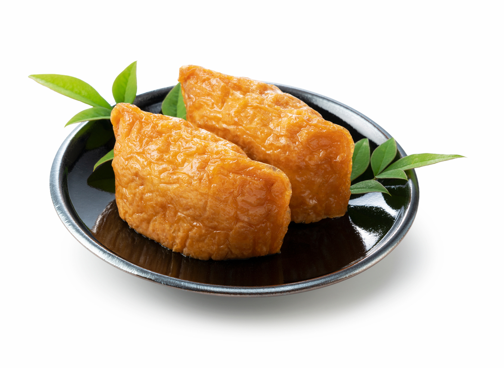 Japanese,Inari,Sushi,On,A,Black,Plate,Set,Against,A